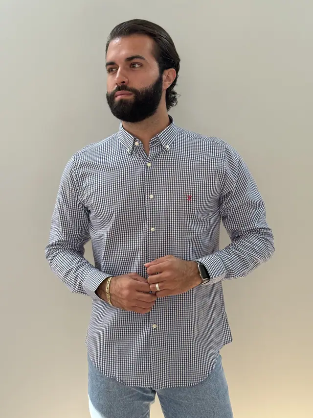 Modelo veste a camisa Long 8XM: xadrez miúdo marinho e branco de manga longa, com monograma bordado no peito.