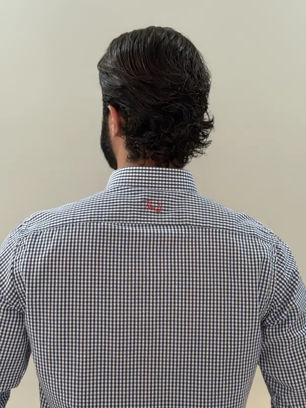 Costas da camisa Long 8XM: assinatura Tbull bordada em vermelho sobre o xadrez miúdo.