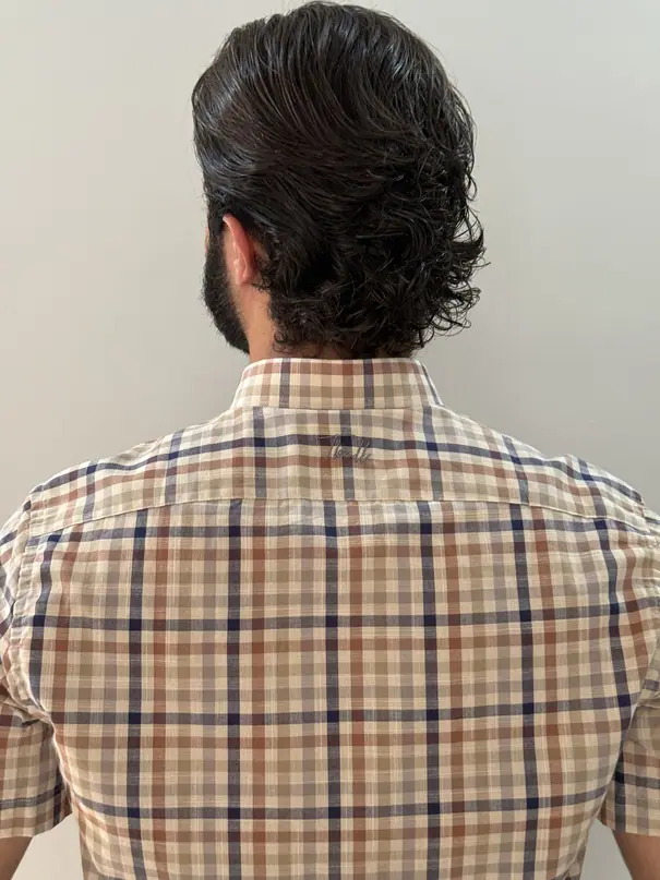 Costas da camisa Cacau: pala costurada e assinatura Tbull bordada em tom sobre tom abaixo do colarinho.