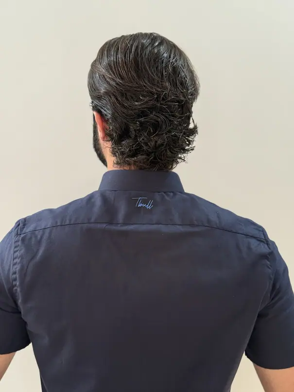 Costas da camisa Marinho OX: assinatura Tbull bordada em azul claro sobre a pala azul-marinho.
