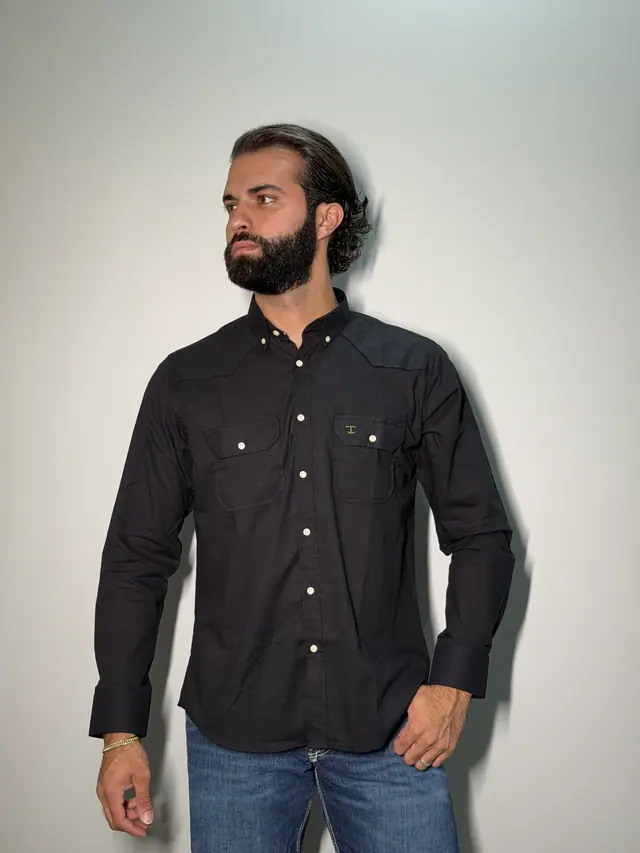 Macro da carcela de uma camisa preta TBull com bolsos western, mostrando os botões em tom osso alinhados.