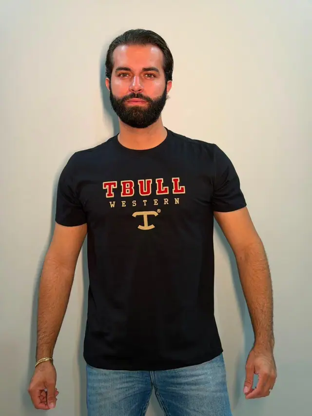 Homem de camiseta preta com a estampa TBULL WESTERN em vermelho e dourado no peito.
