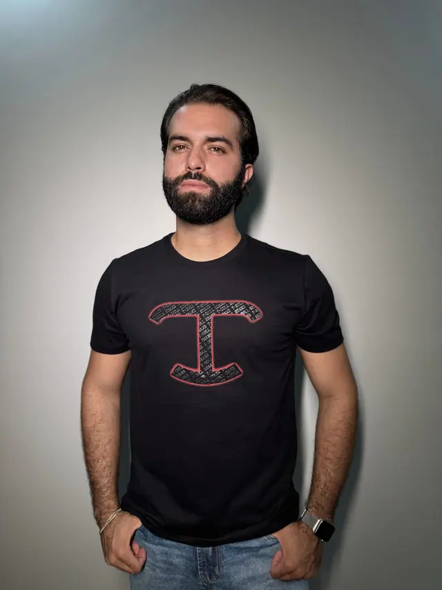 Homem de camiseta preta de malha com o monograma T em vermelho no centro do peito.