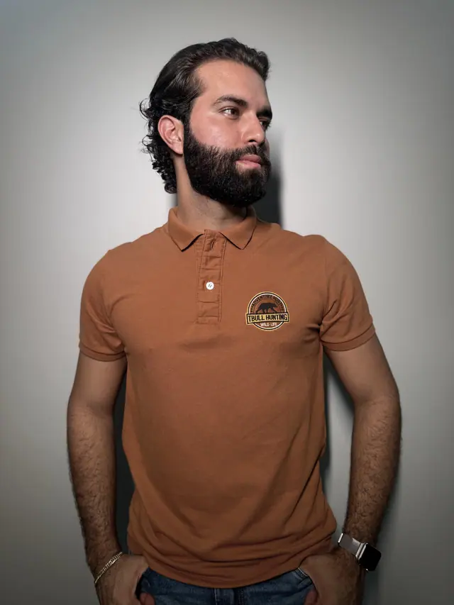 Modelo veste a polo Brutus: piquê caramelo com brasão circular bordado no peito.