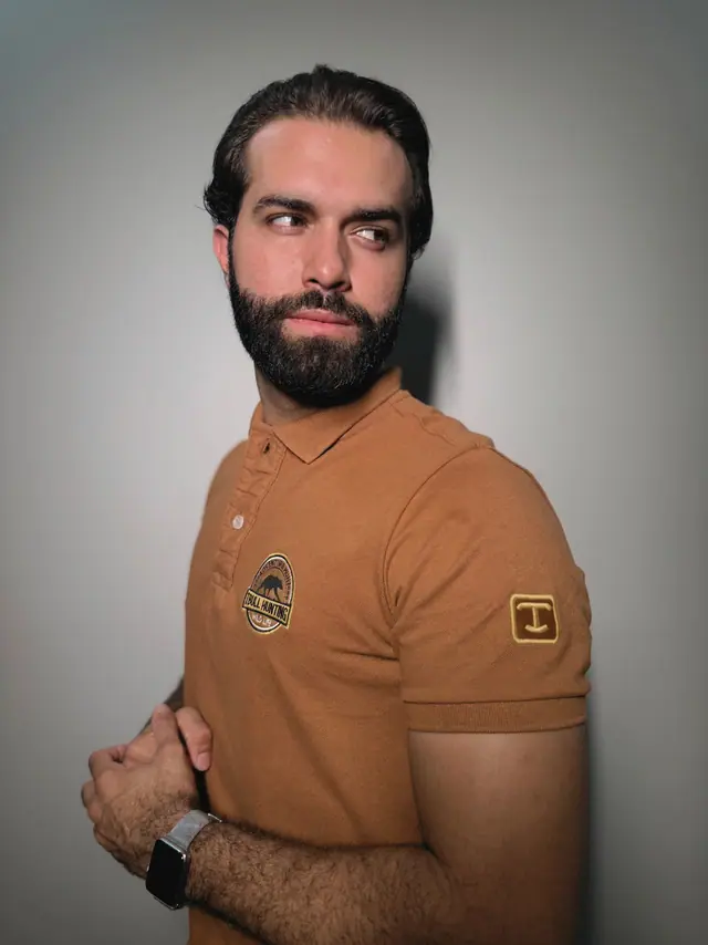 Polo Brutus em três quartos: brasão bordado no peito e etiqueta com o monograma T aplicada na manga.
